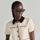 Woman in a cream short-sleeve collared shirt and Naomi - Polished Black sunglasses by KayTran Eyewear.