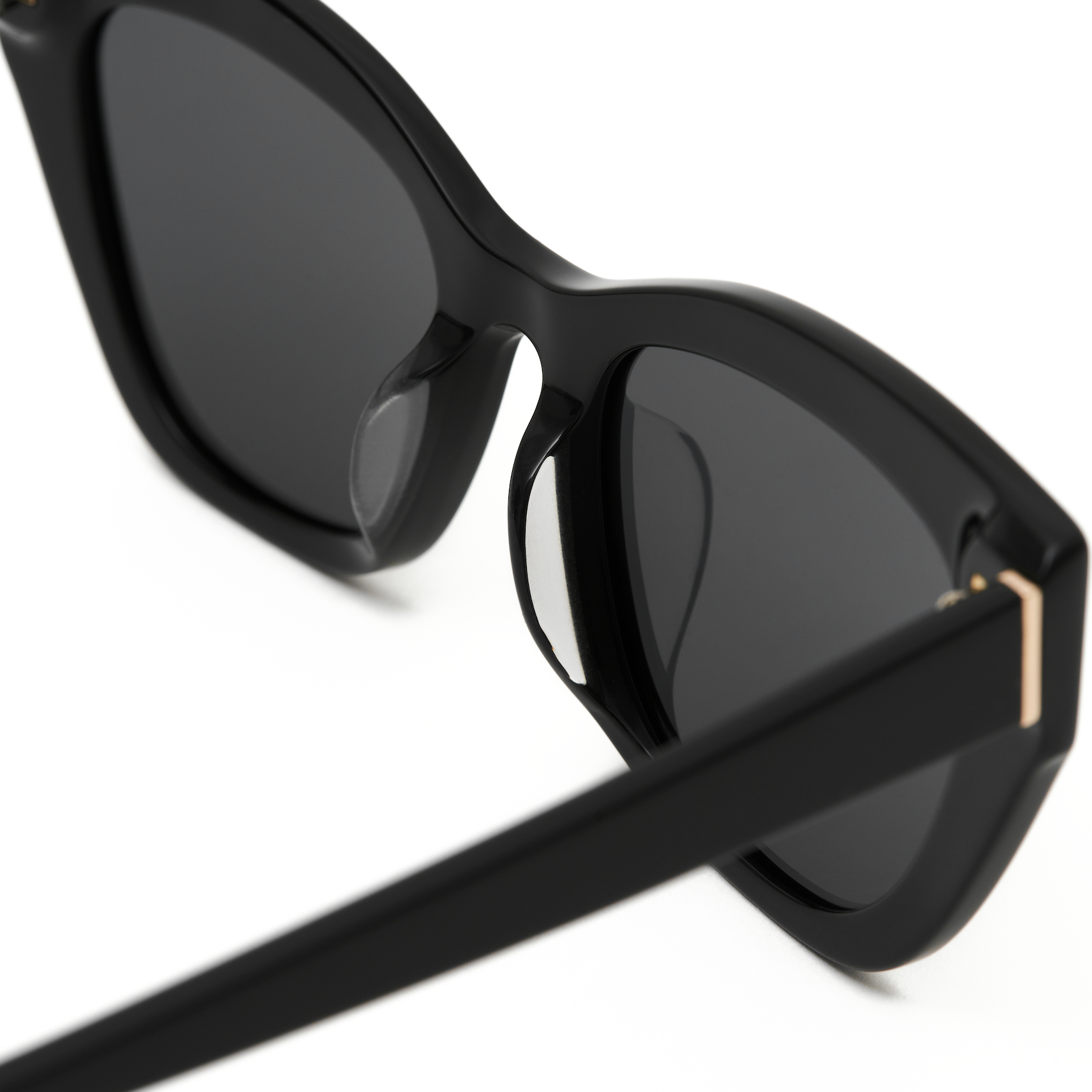 Close-up of KayTran Eyewears Harper - Polished Black sunglasses with dark lenses and gold accents.