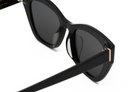 Close-up of KayTran Eyewears Harper - Polished Black sunglasses with dark lenses and gold accents.