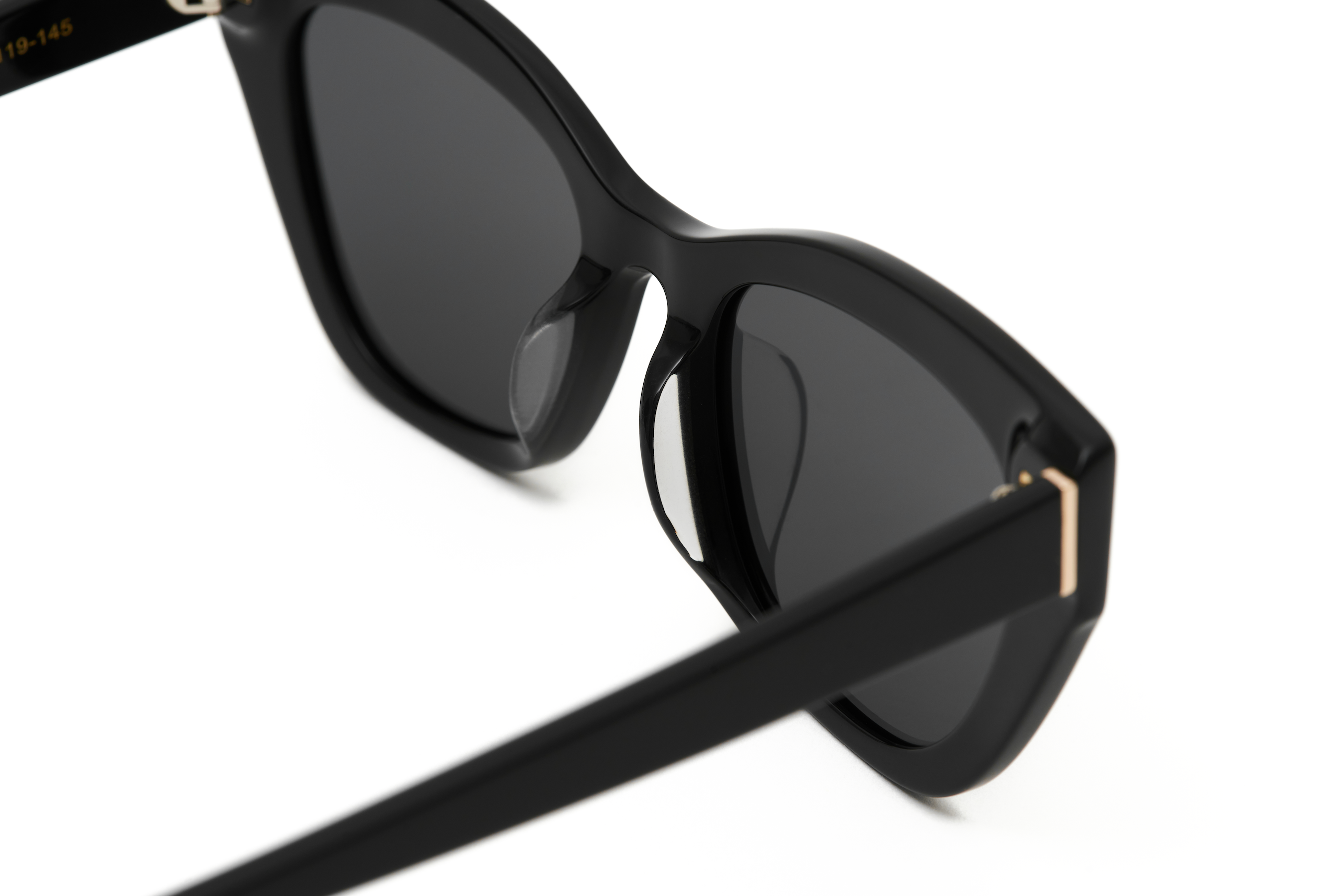 Close-up of KayTran Eyewears Harper - Polished Black sunglasses with dark lenses and gold accents.