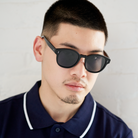 Man with short hair and beard wears KayTran Eyewears Reese - Polished Black sunglasses and a navy collared shirt.