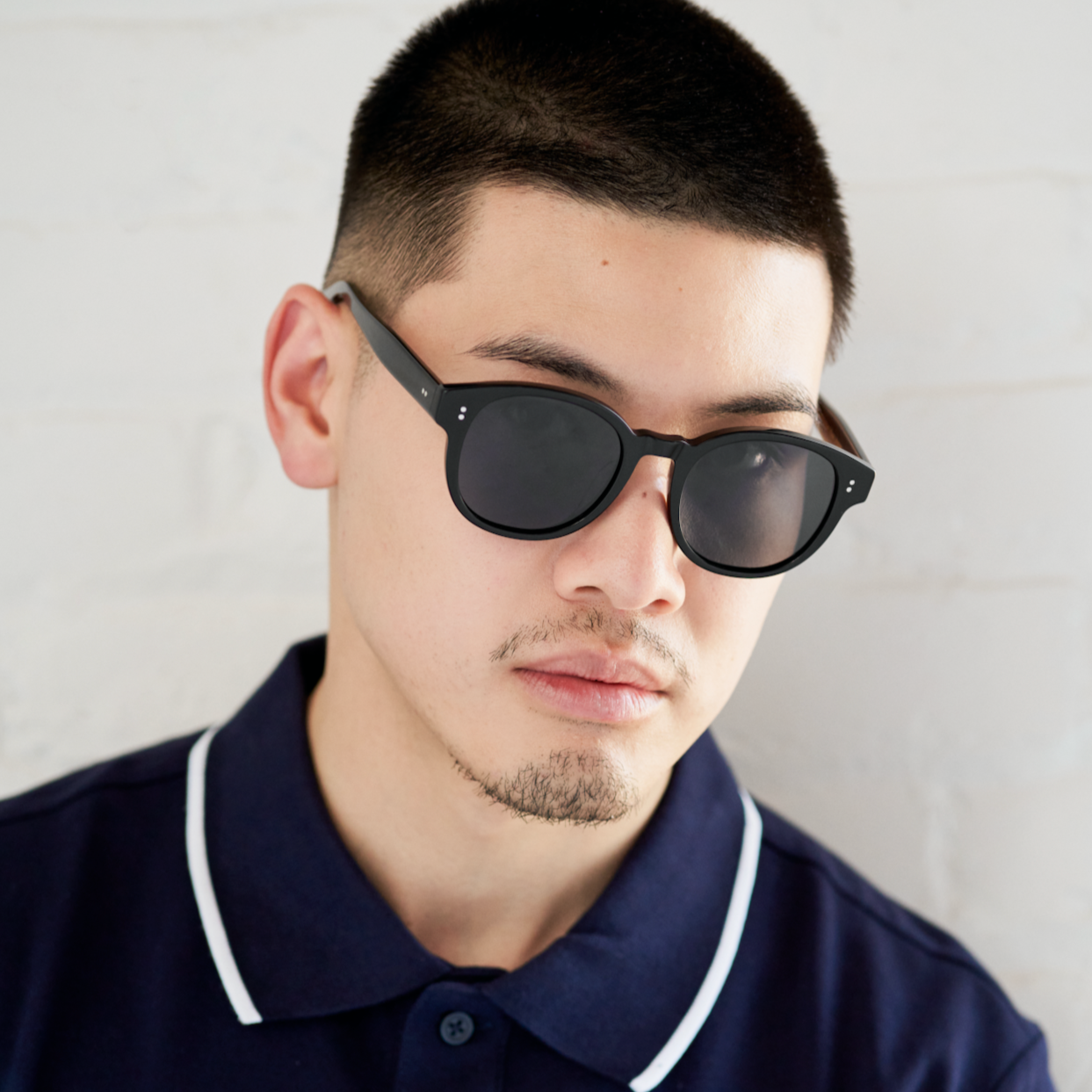 Man with short hair and beard wears KayTran Eyewears Reese - Polished Black sunglasses and a navy collared shirt.