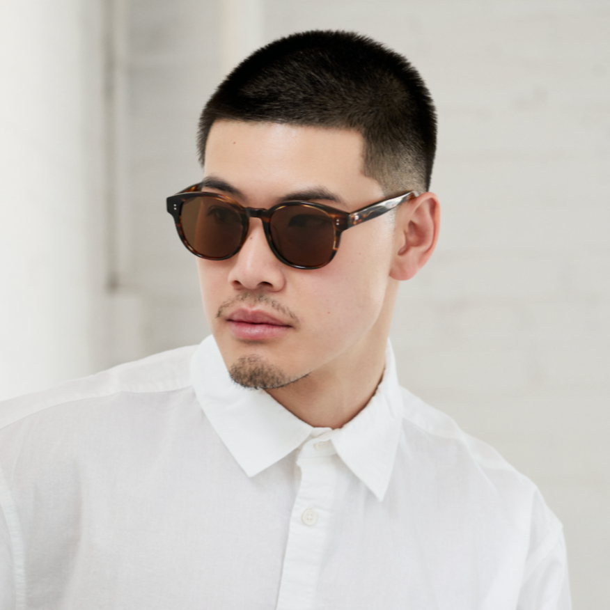 Man with short hair in KayTran Eyewears Reese - Amber Honey sunglasses and a white button-up shirt.