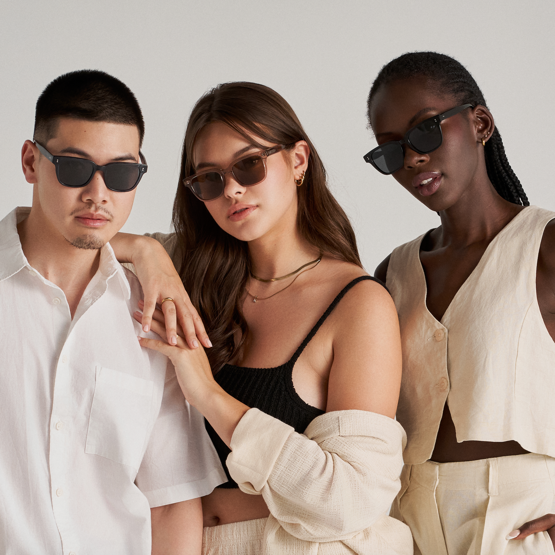 Three people wear KayTran Eyewear’s Charlie - Dark Denim sunglasses with neutral outfits against a plain background.