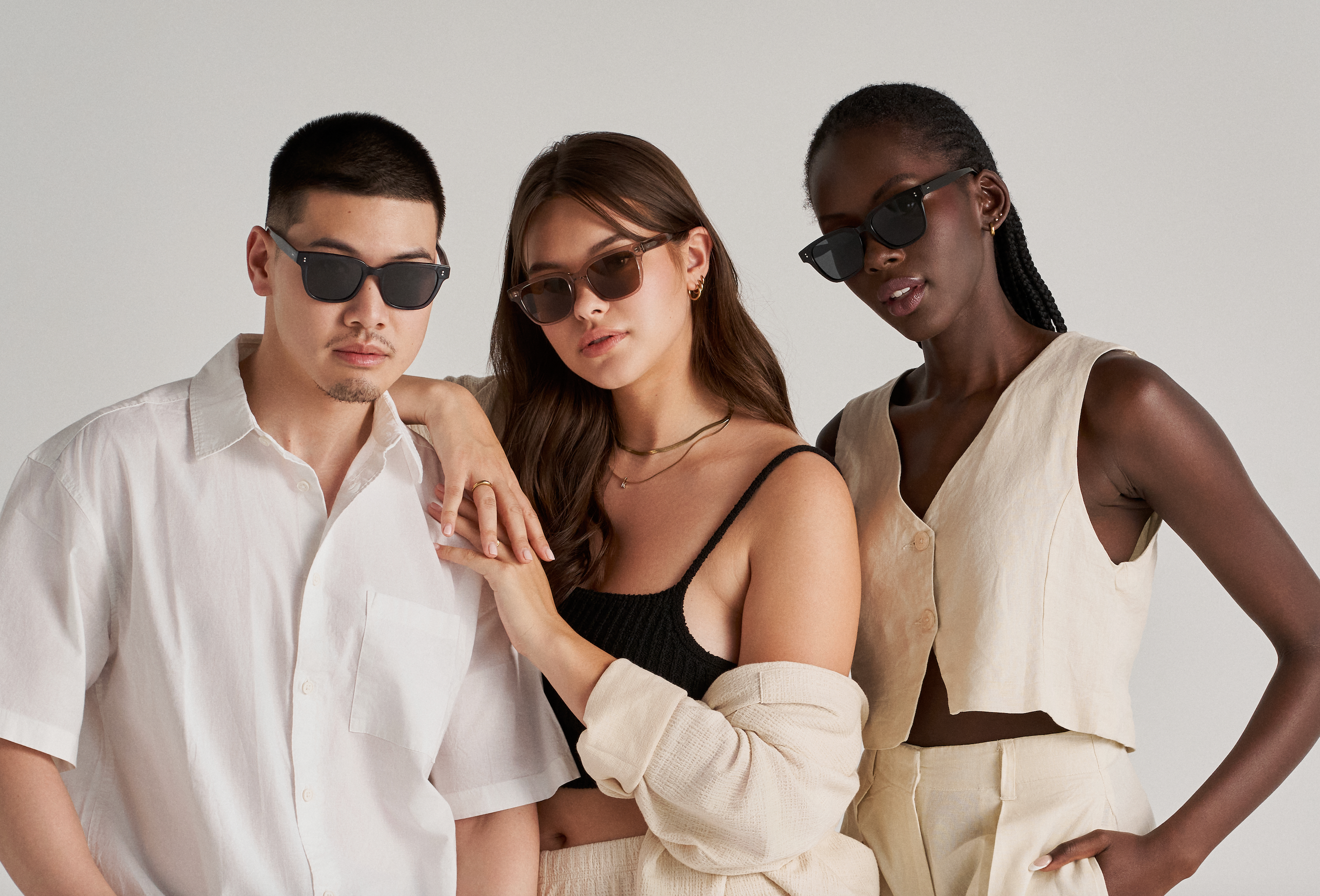 Three people wear KayTran Eyewear’s Charlie - Dark Denim sunglasses with neutral outfits against a plain background.