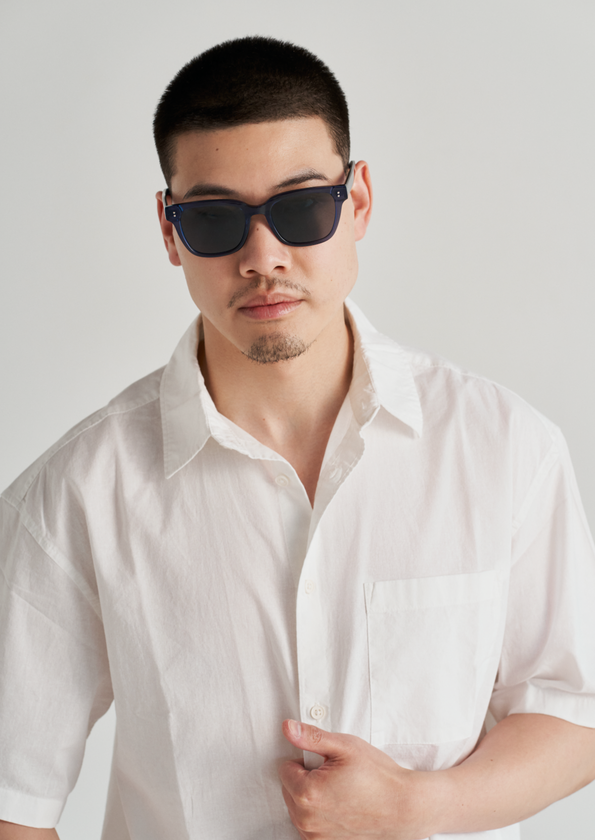 Man wears KayTran Eyewears Charlie - Dark Denim sunglasses and a white short-sleeve shirt, facing the camera.