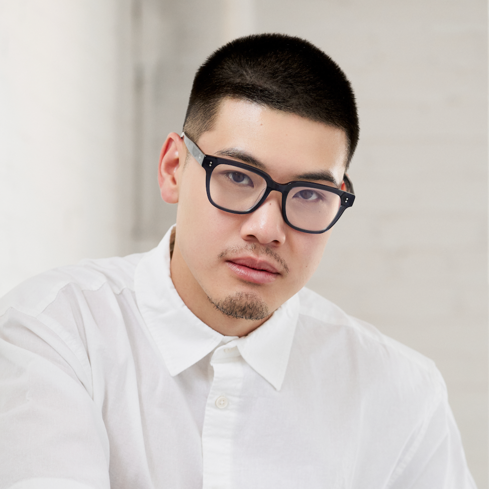 A man with short hair, a trimmed goatee, and black KayTran Eyewear Charlie Optical - Dark Denim glasses in white shirt.