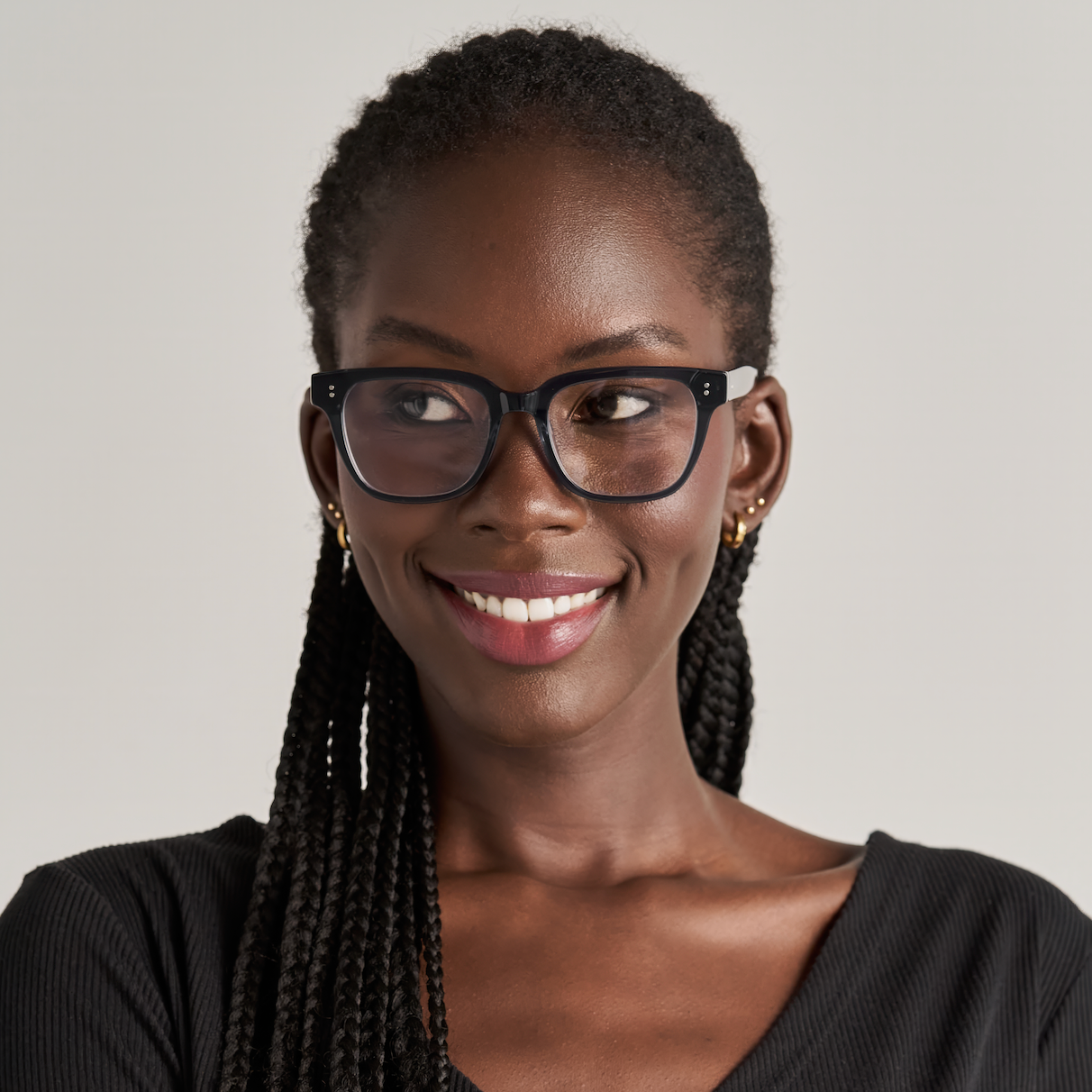Woman with braided hair wears KayTran Eyewears Charlie Optical - Dark Denim glasses, smiling against a plain background.