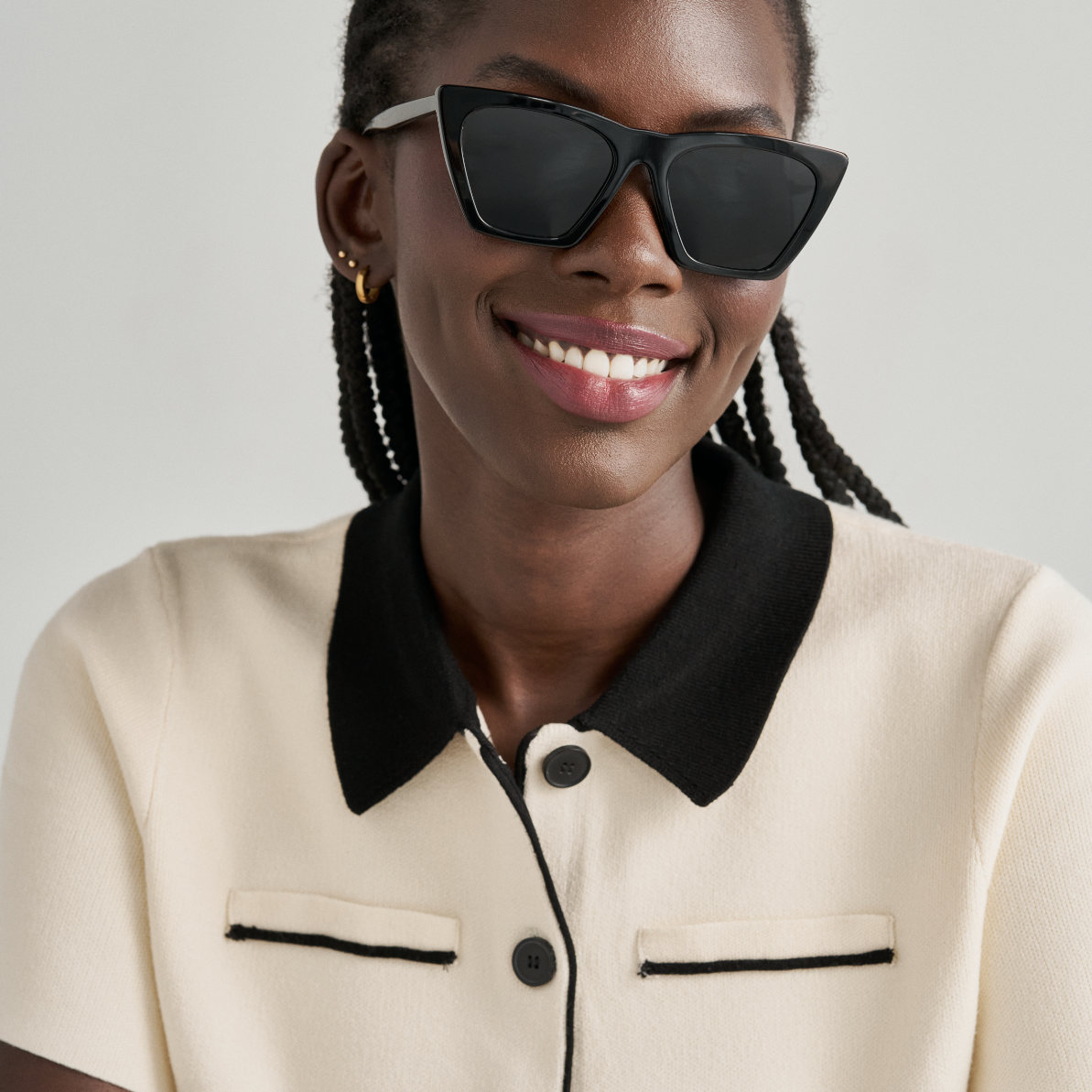 Woman smiling with arms crossed, wearing KayTran Eyewear Frankie - Polished Black sunglasses and a cream top.