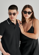 A man and a woman wear KayTran Eyewears Reese - Polished Black sunglasses against a plain light background.