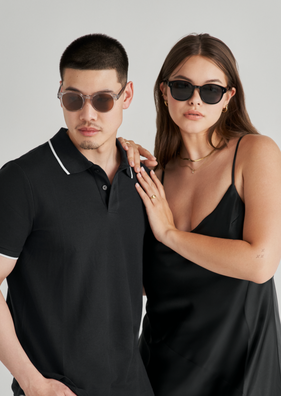 A man and a woman wear KayTran Eyewears Reese - Polished Black sunglasses against a plain light background.