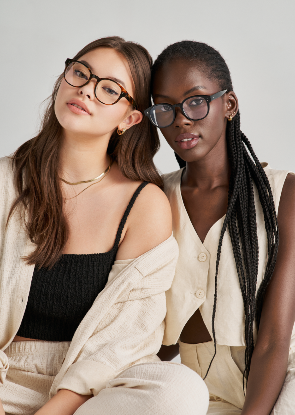 Two women wear KayTran Eyewears Reese Optical - Fog glasses with neutral outfits, facing the camera.
