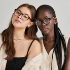 Two women wear KayTran Eyewears Reese Optical - Polished Black glasses with neutral tops against a light background.