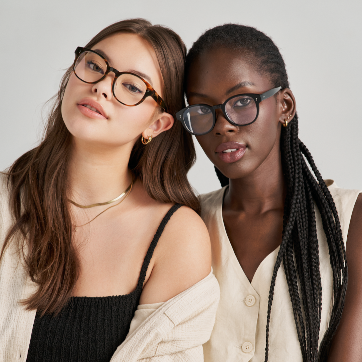 Two women wear KayTran Eyewears Reese Optical - Polished Black glasses with neutral tops against a light background.