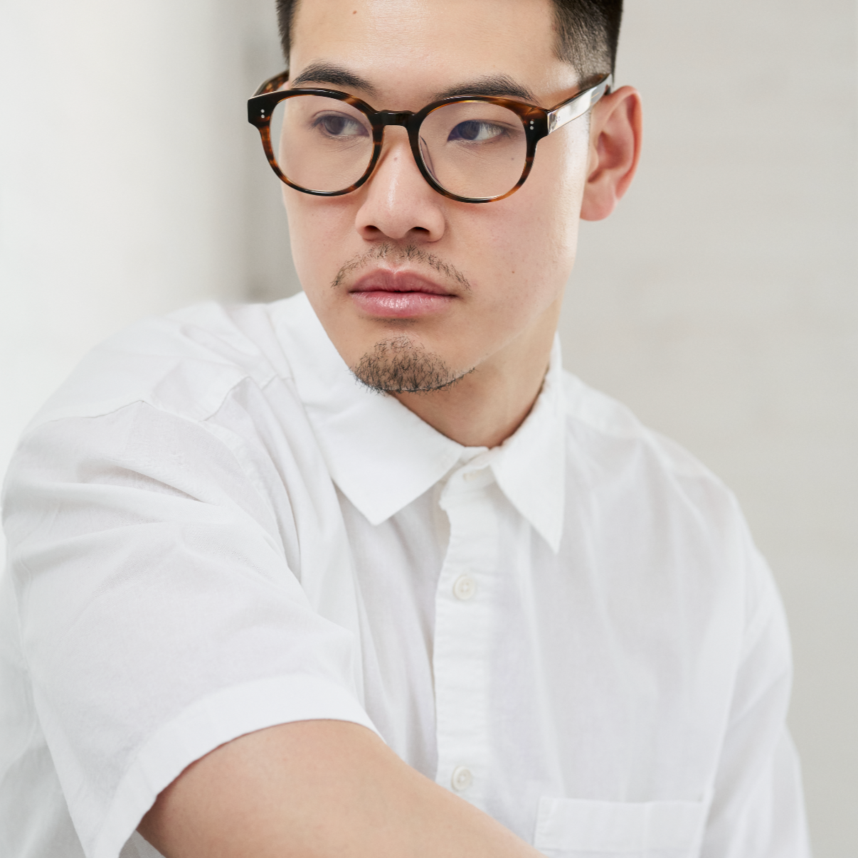 Man wears KayTran Eyewear Reese Optical - Polished Black glasses, looking to the side against a light background.