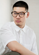 Man wears KayTran Eyewear Reese Optical - Polished Black glasses, looking to the side against a light background.