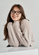 Woman with long brown hair smiles in KayTran Eyewears Taylor Optical - Polished Black glasses and a beige sweater.