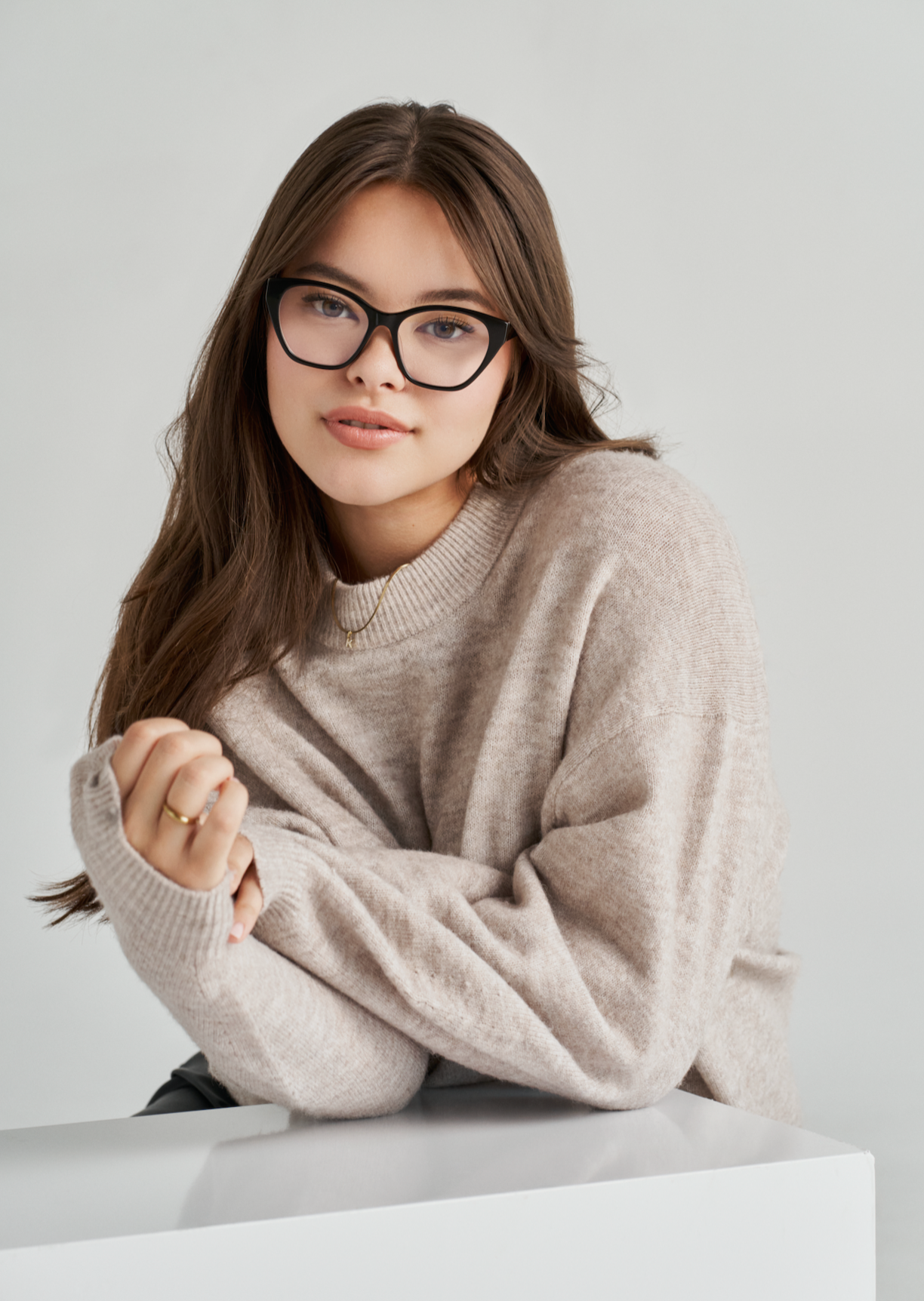 Young woman wearing KayTran Eyewears Taylor Optical - Polished Black, beige sweater, against a plain light background.