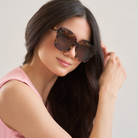 Woman with long dark hair wearing KayTran Eyewear Logan - Ember & Brown Lens sunglasses and a pink top.
