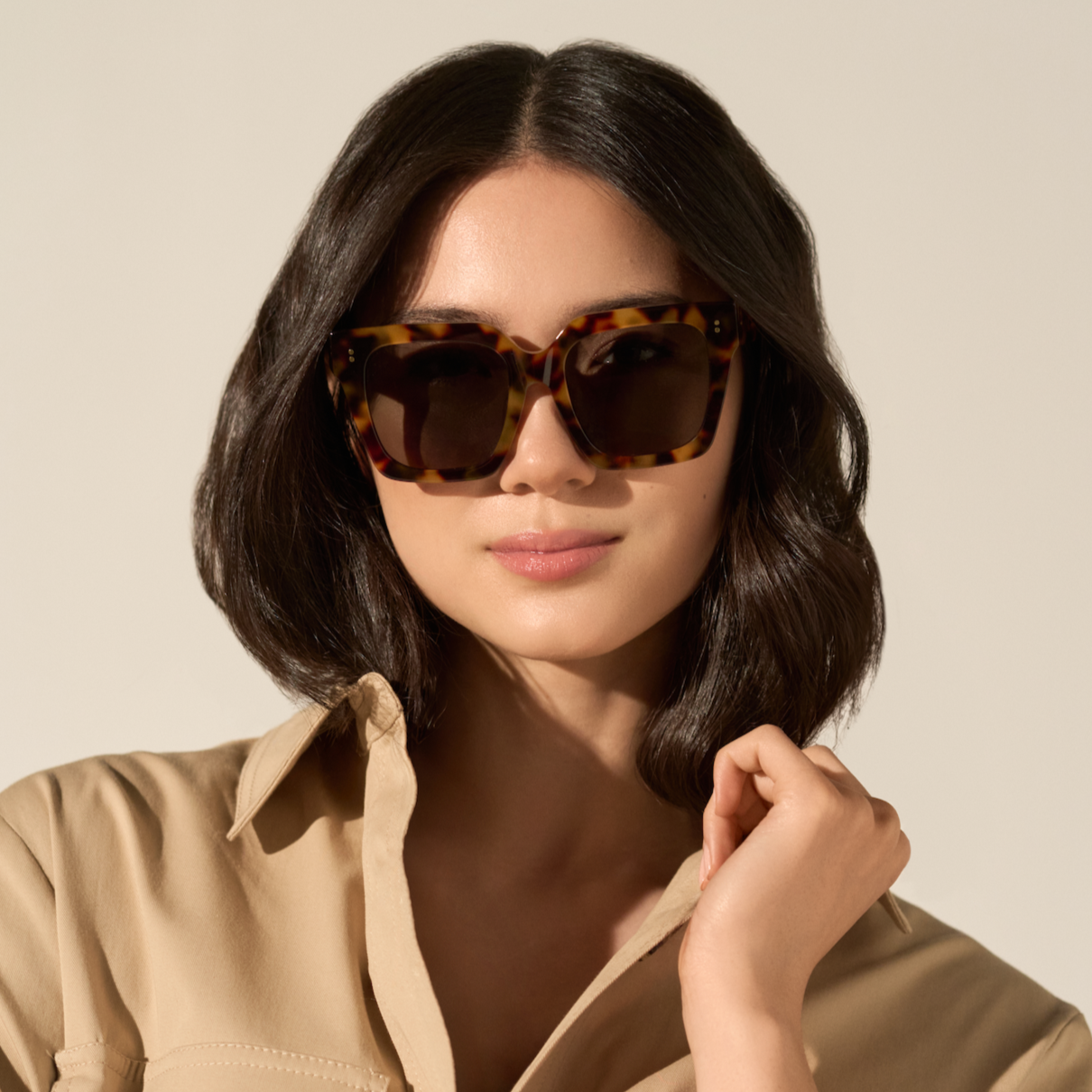 Woman wearing KayTran Eyewear Logan - Ember & Grey Lens sunglasses, beige shirt, and dark bob hairstyle.