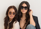 Two women wear KayTran Eyewears Logan - Polished Black sunglasses against a plain white background.