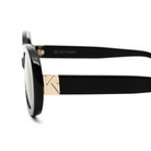 Close-up side view of Mara - Polished Black by KayTran Eyewear, featuring gold arm hinge detailing on white background.