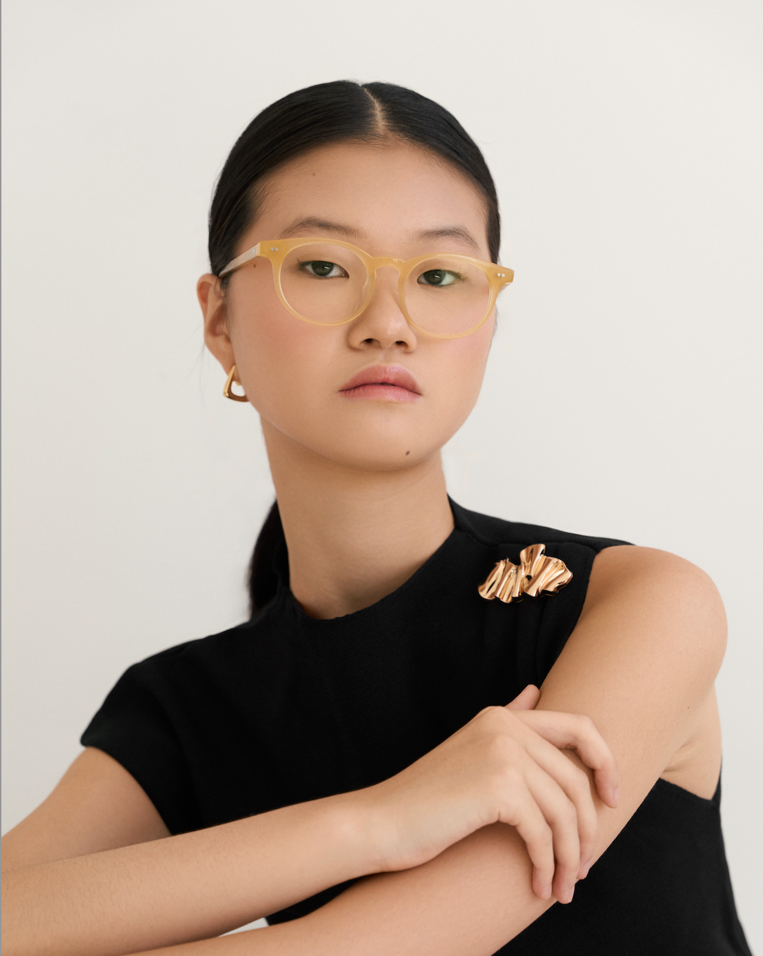 Model wears KayTran Eyewears Bailey - Milky Honey, styled with a black sleeveless top and gold accessories.