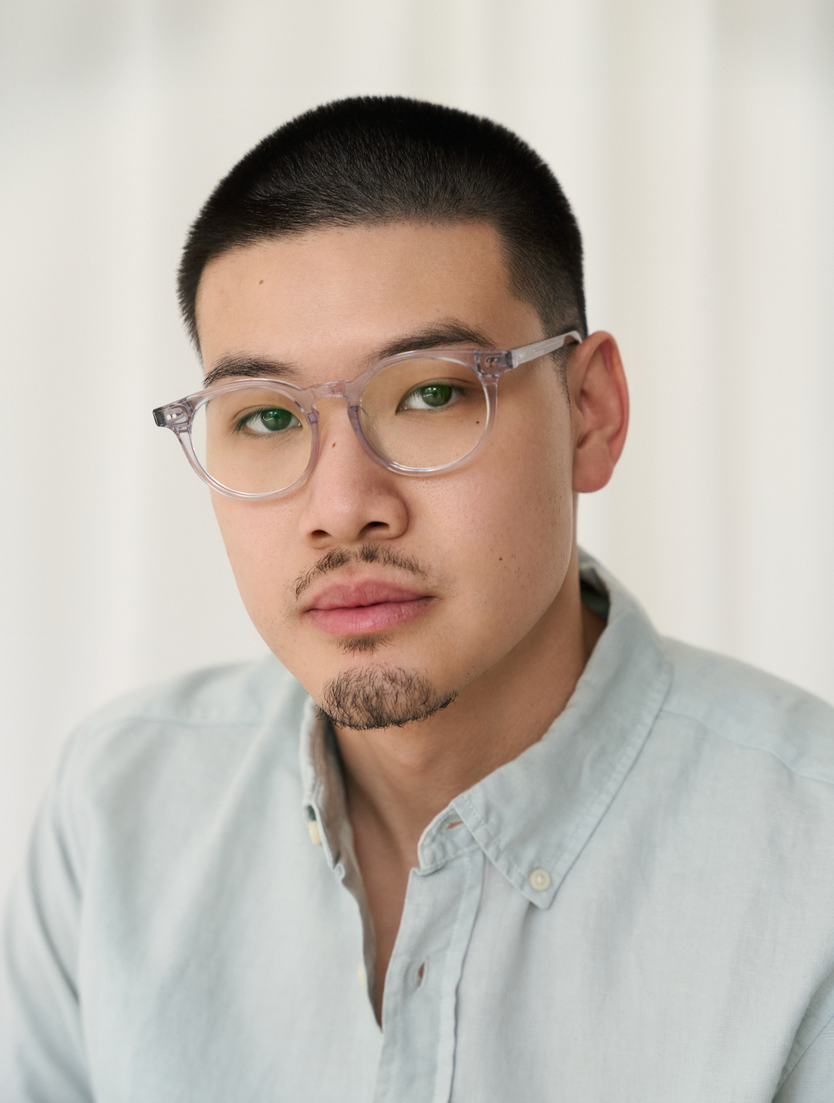 A man in a light blue shirt wears KayTran Eyewears Bailey - Mist glasses, looking at the camera against a light background.
