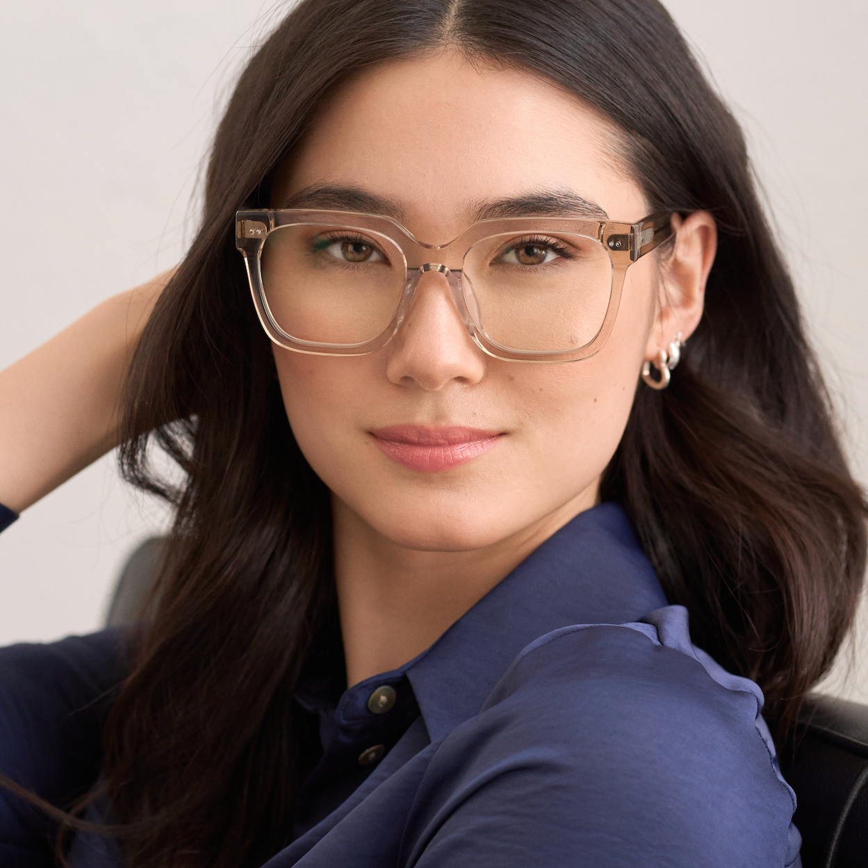 Woman with long dark hair wears KayTran Eyewears Andy - Sand glasses and a navy shirt, looking at the camera.