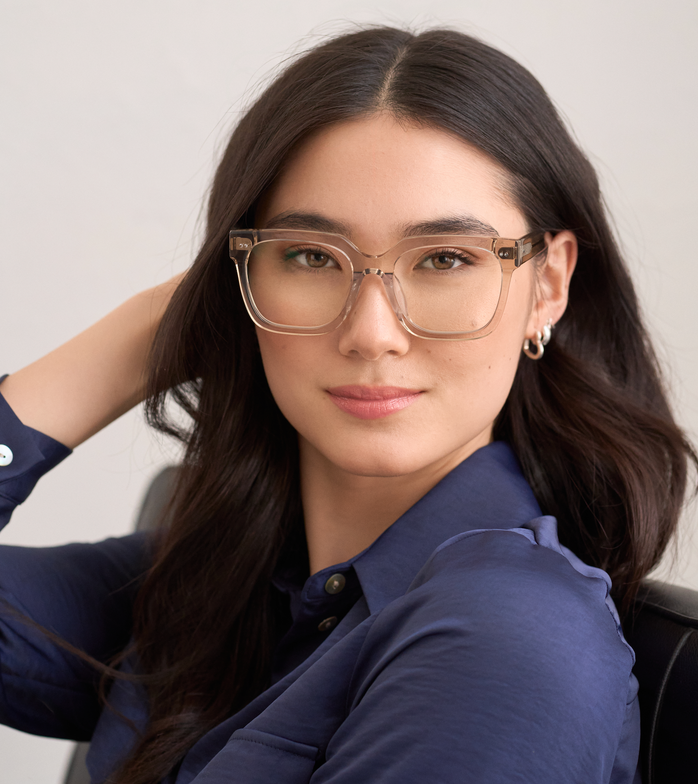 Woman with long dark hair wears KayTran Eyewears Andy - Sand glasses and a navy shirt, looking at the camera.