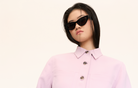 Model wears KayTran Eyewear’s Drew - Polished Black sunglasses with a light pink button-up shirt against a plain background.