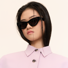 A woman with straight dark hair wears KayTran Eyewears Drew - Polished Black sunglasses and a light pink collared shirt.
