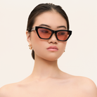 Woman wears KayTran Eyewears Kai - Black and Peach *Limited Edition* sunglasses, gazing sideways against a plain background.