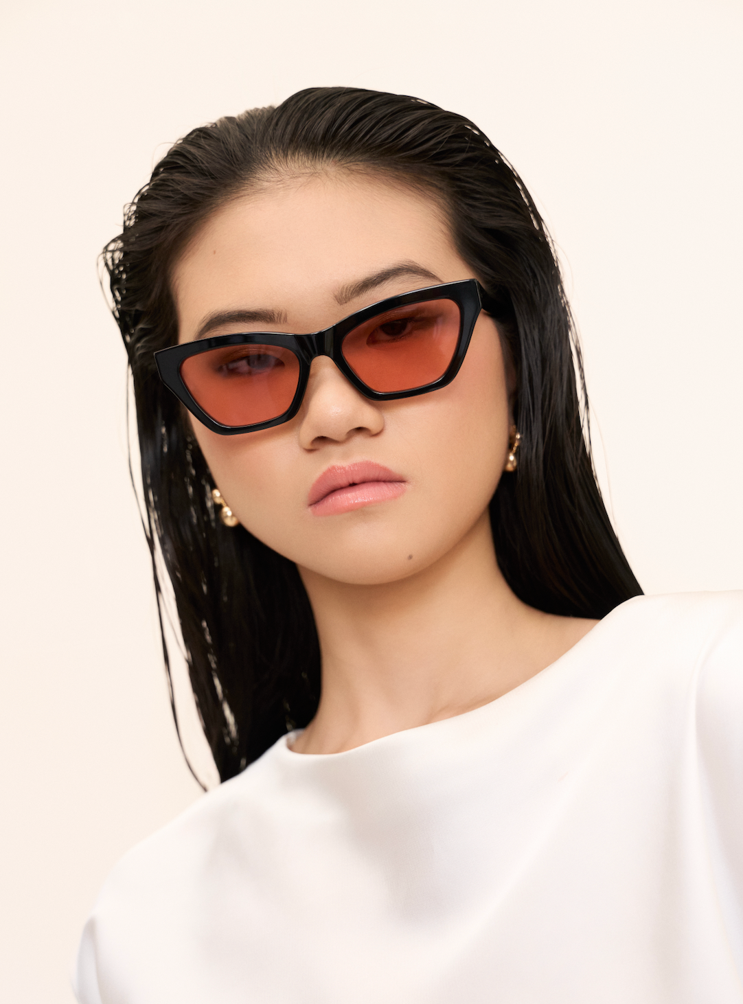 Woman with straight black hair wears KayTran Eyewears Kai - Black and Peach *Limited Edition* sunglasses, white top.