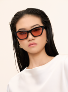 Woman with straight black hair wears KayTran Eyewears Kai - Black and Peach *Limited Edition* sunglasses, white top.