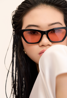 A woman with wet black hair wears KayTran Eyewears Kai - Black and Peach *Limited Edition* sunglasses, facing the camera.