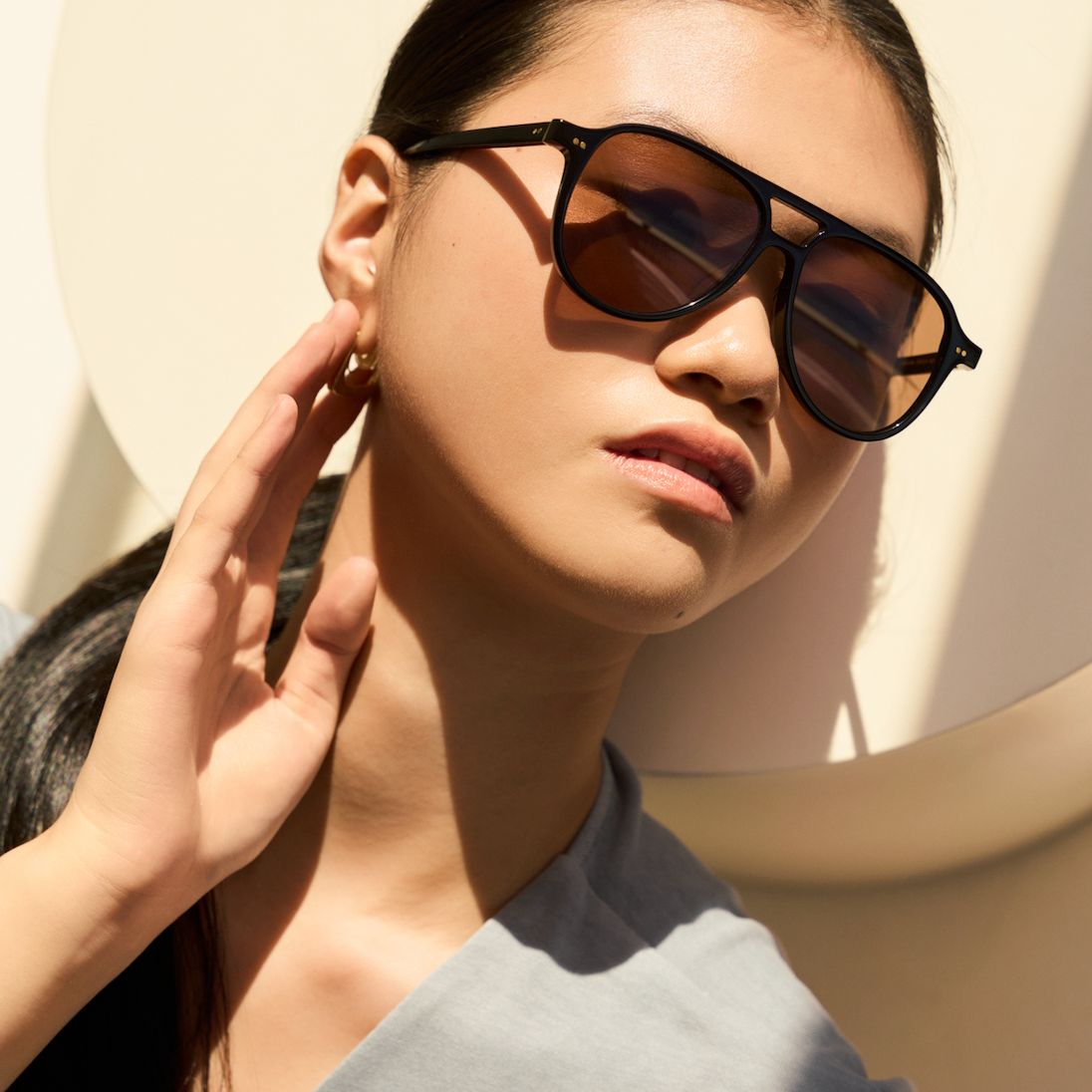 A woman wears KayTran Eyewears Knox sunglasses with black & brown lenses, posing for a picture.