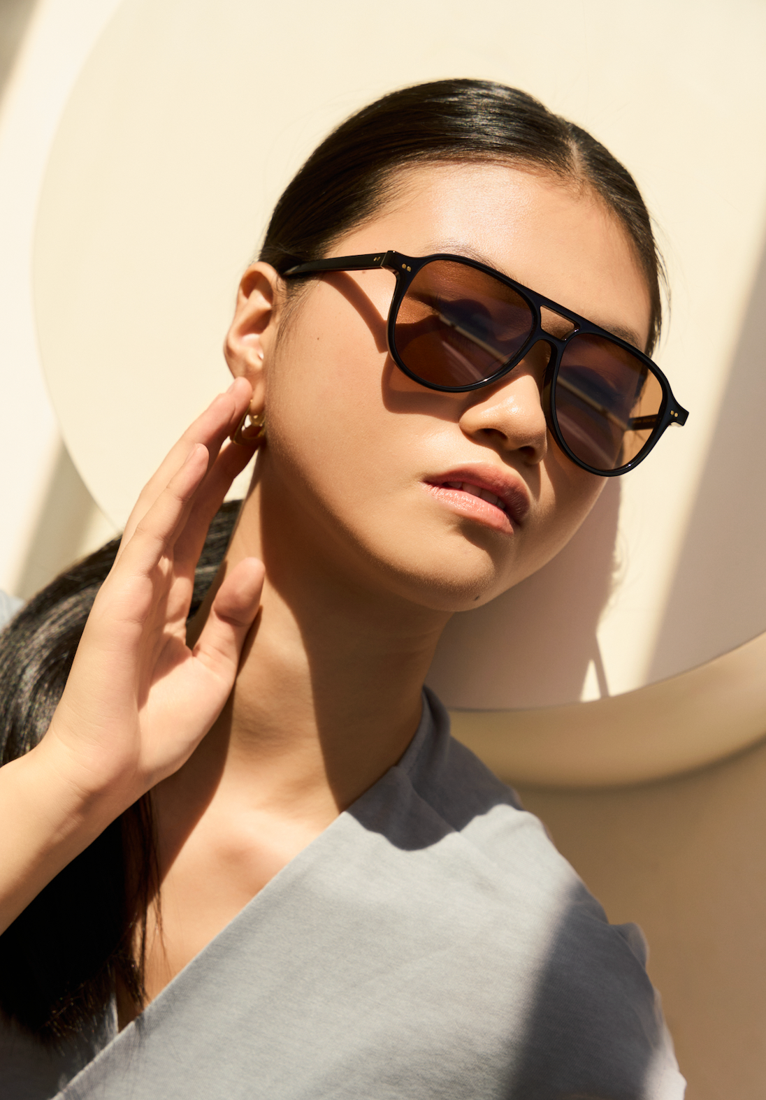 A woman wears KayTran Eyewears Knox sunglasses with black & brown lenses, posing for a picture.