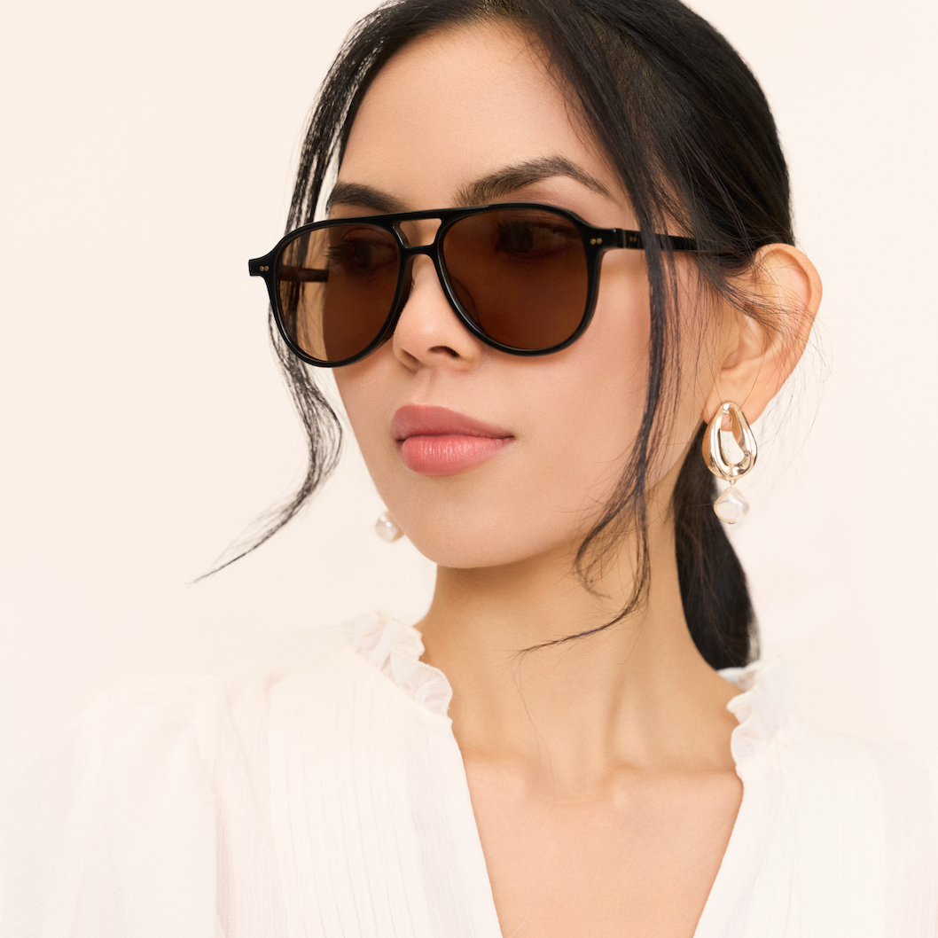 Woman in Knox - Black & Brown Lens by KayTran Eyewear, pearl drop earrings, white blouse, against a plain background.