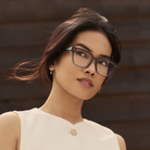 Woman with long dark hair wears KayTran Eyewears Charlie Optical - Sage glasses and a sleeveless white top.