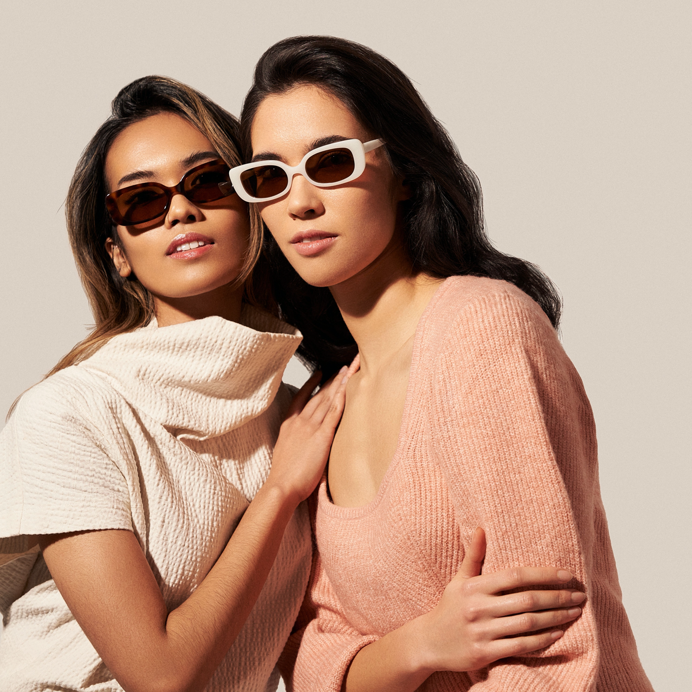Two women in neutral outfits wear KayTran Eyewears Billie - Lava Tortoise sunglasses against a plain light background.