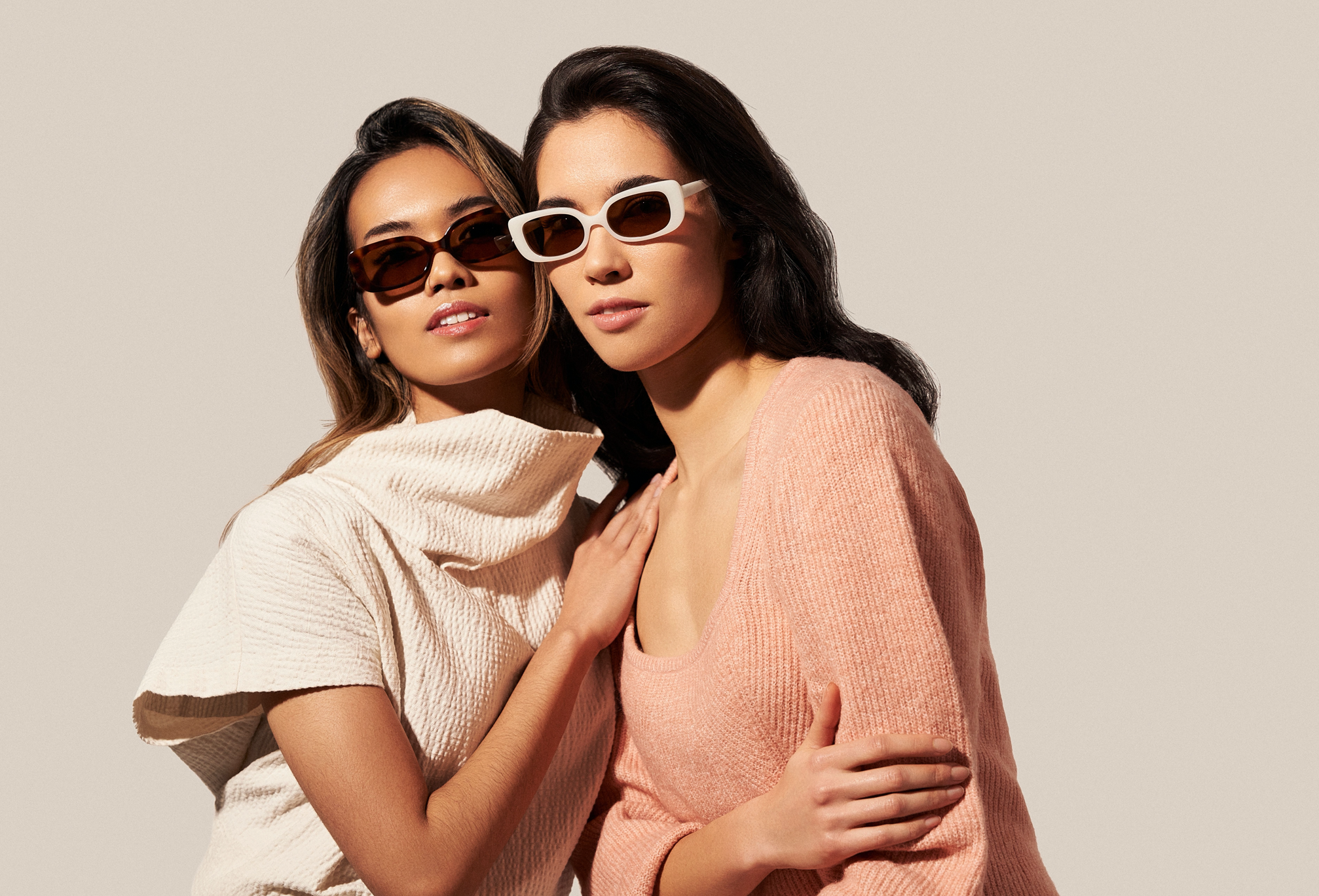 Two women in neutral outfits wear KayTran Eyewears Billie - Lava Tortoise sunglasses against a plain light background.