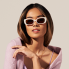 Woman with straight brown hair in KayTran Eyewear Billie - Ivory sunglasses, lilac top, and matching sweater.
