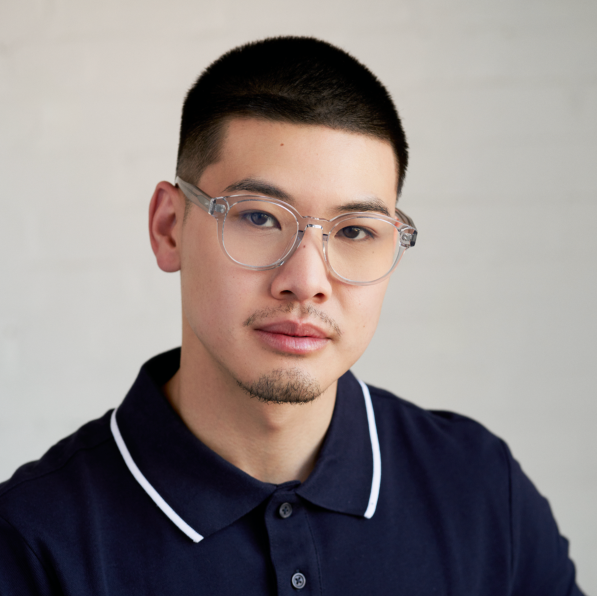 A man with short hair wears KayTran Eyewears Reese Optical - Fog glasses, facing the camera against a light backdrop.