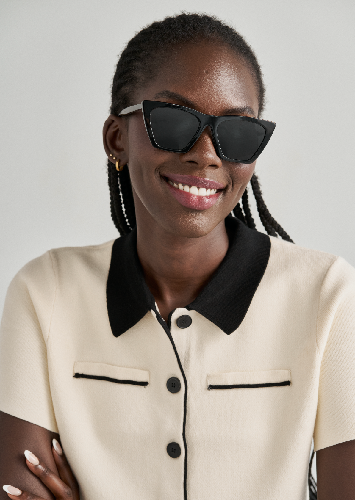 Woman smiling with arms crossed, wearing KayTran Eyewear Frankie - Polished Black sunglasses and a cream top.