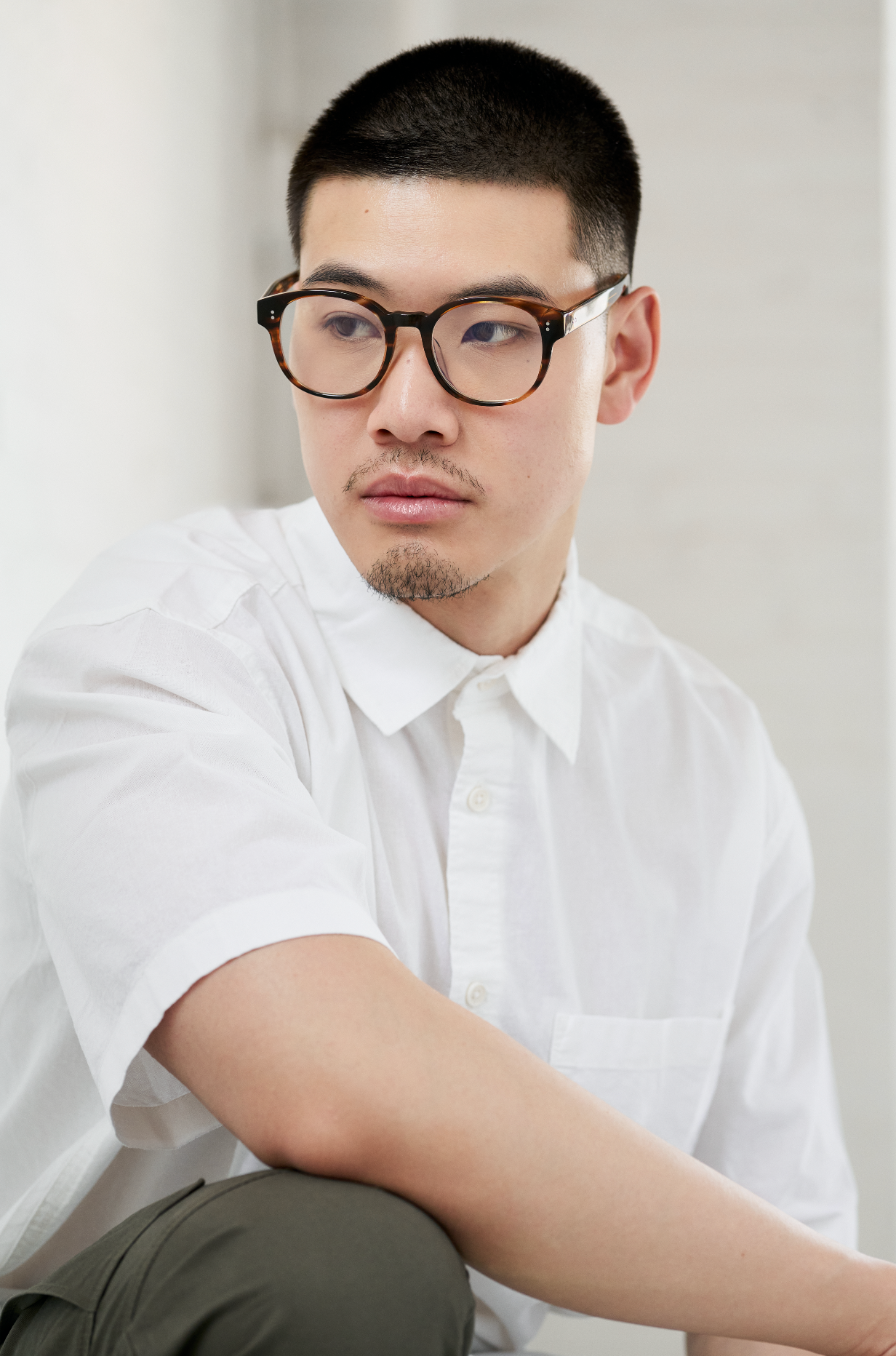 A man with short hair wears Reese Optical - Amber Honey glasses by KayTran Eyewear, looking to the side.