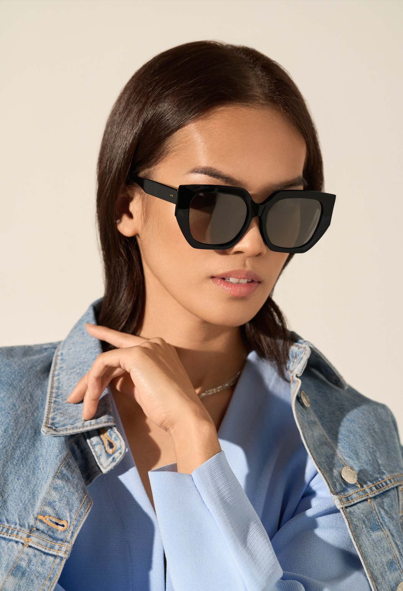 Woman wearing Luna - Polished Black by KayTran Eyewear, blue top, and denim jacket against a neutral background.