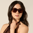 Woman with long dark hair wears KayTran Eyewears River - Lava Tort sunglasses, looking to the side.