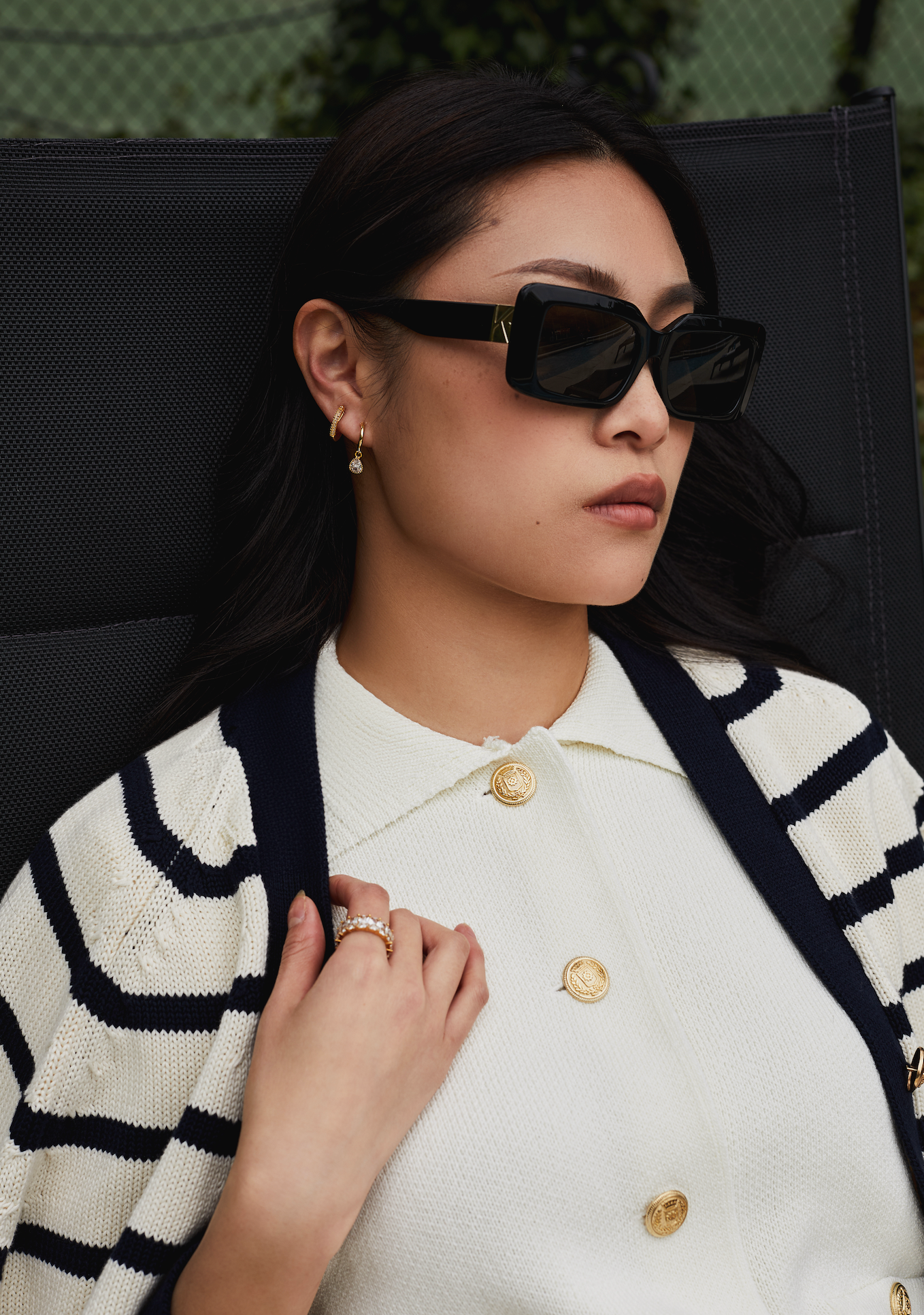 Woman wearing KayTran Eyewear’s Brooks - Polished Black sunglasses, lounging outdoors in a white sweater.