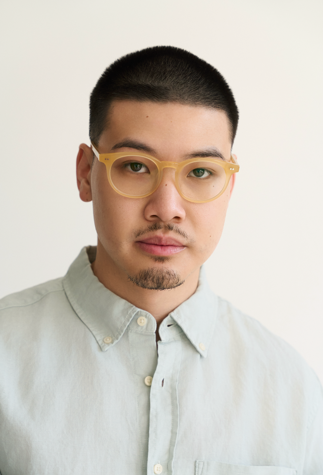 A man with short hair and a goatee wears KayTran Eyewears Bailey - Milky Honey glasses and a light grey shirt.